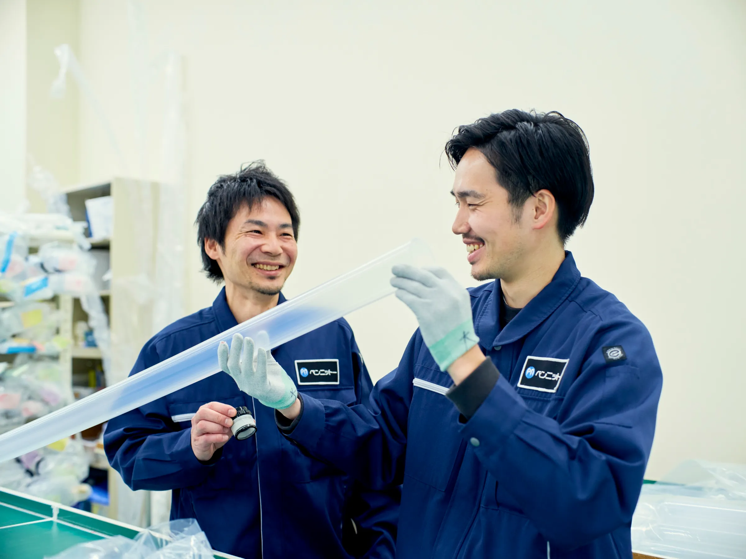 ふっ素樹脂チューブを手に笑顔で話す社員2名
